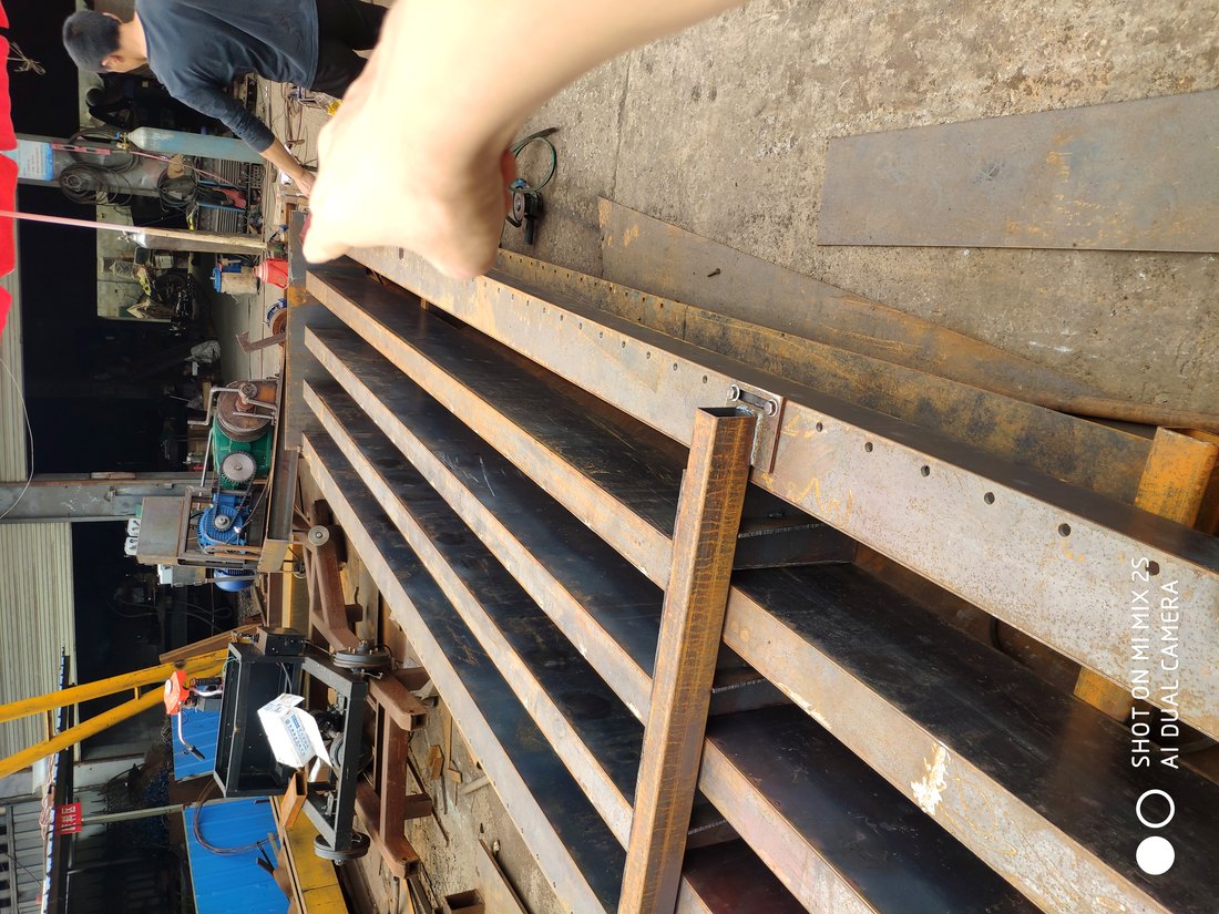 Worker placing reinforcement bars by hand in a steel precast beam casting bed